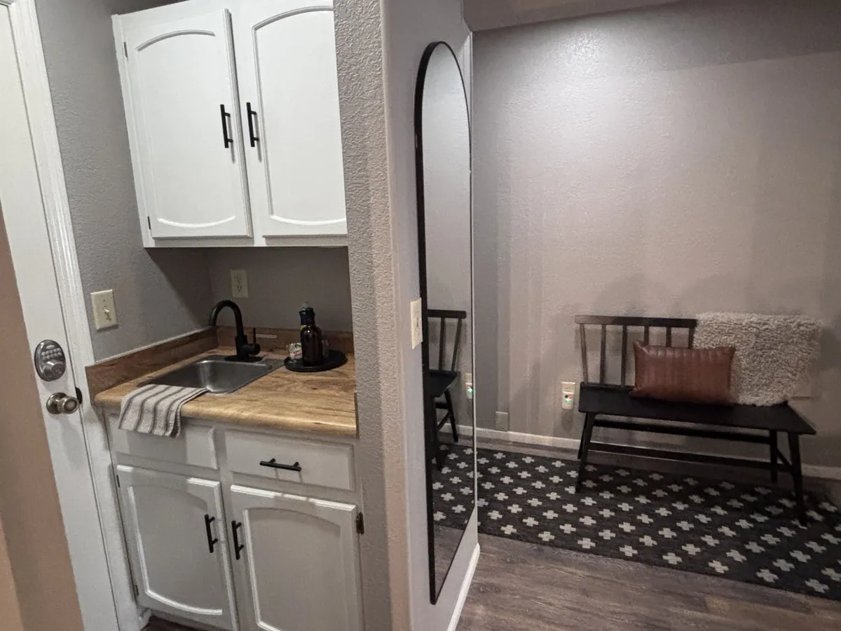 A cozy area featuring a sink, large mirror, and a bench, accented with soft lighting. This inviting nook is ideal for morning coffee rituals or winding down with evening reflections, embodying the condo’s contemporary comfort.