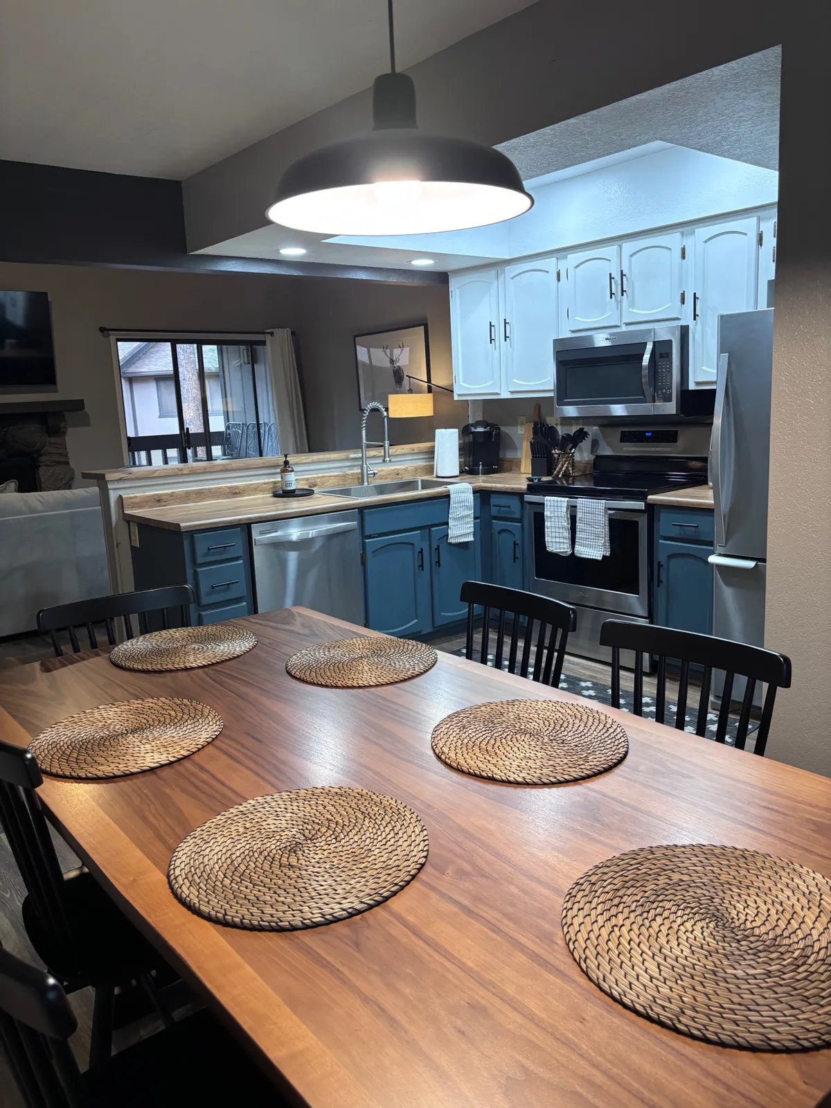 An open-plan kitchen and dining space with striking blue cabinets and a central kitchen island. The setup is perfect for cooking, entertaining, and enjoying meals together, fostering a sense of togetherness and shared experiences.