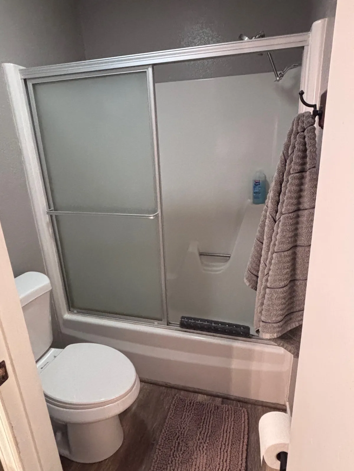 A serene bathroom space with a modern shower, toilet, towel rack, and bath mat. The clean lines and minimal decor create a peaceful atmosphere, inviting guests to unwind after a day exploring the pines.